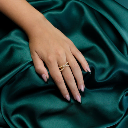 Angled perspective of a model wearing the Beaded Criss Cross Ring against a green backdrop.