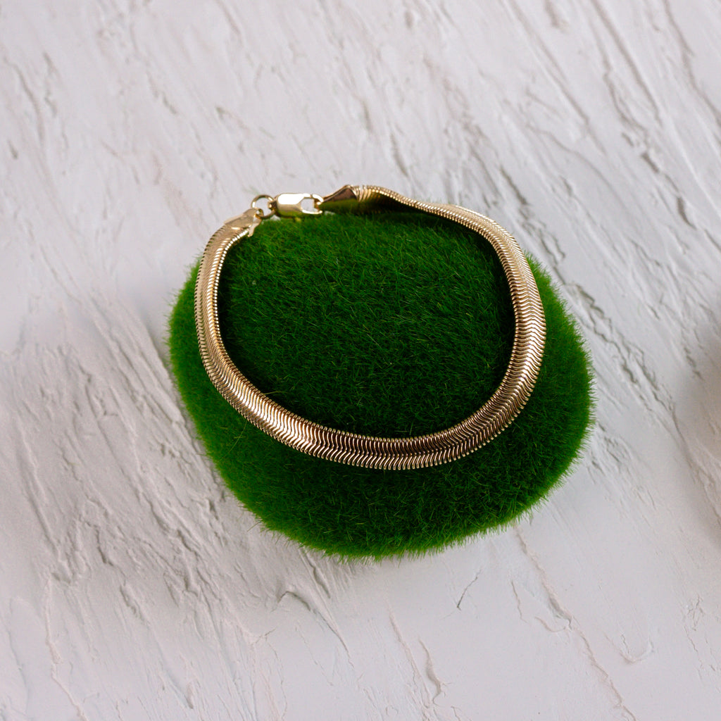 Top view of Gold Snake Chain Bracelet on a fuzzy green rock, highlighting its smooth texture