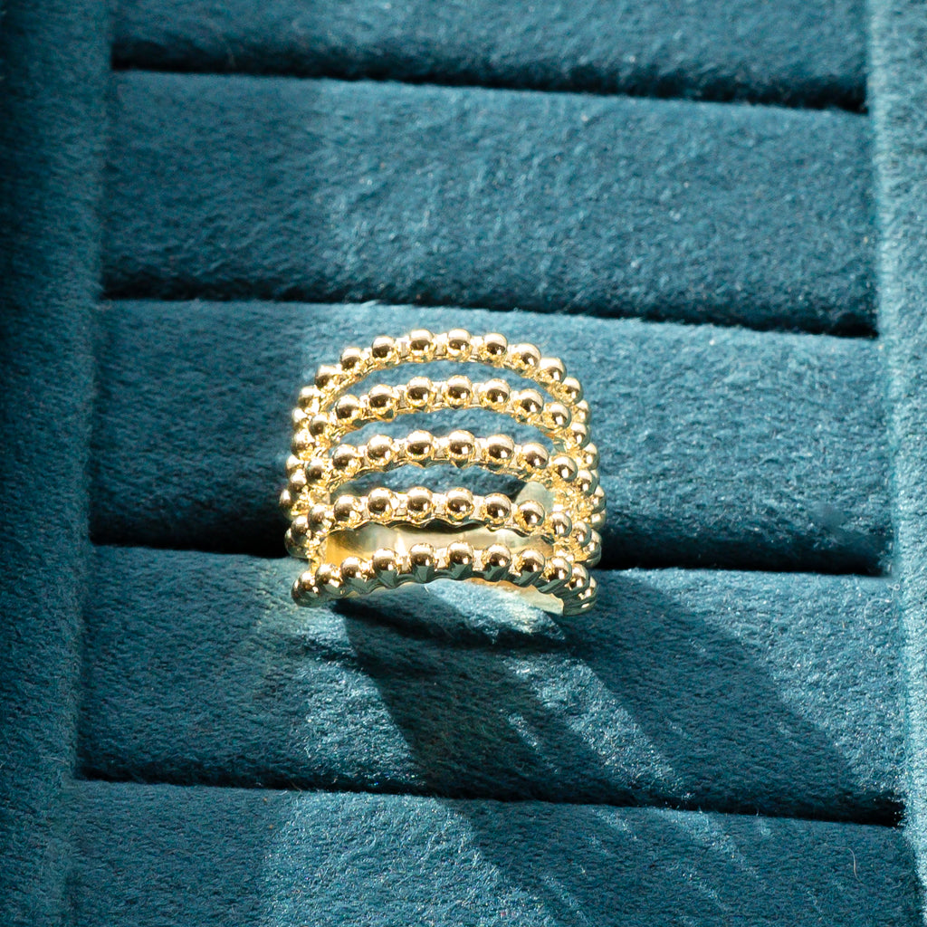 Close-up view showing the intricate beaded strands of the gold ring.