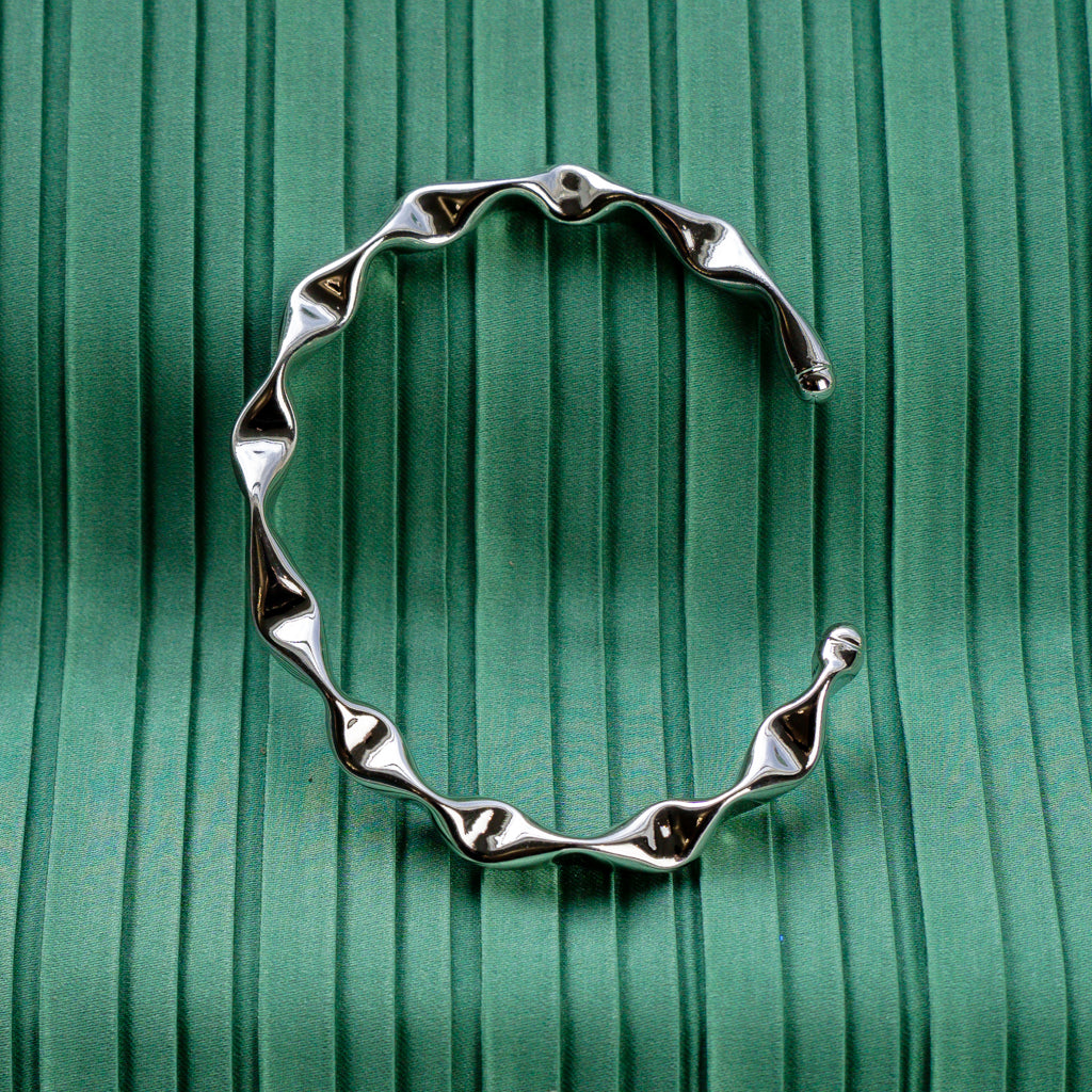 Silver Dented Bangle displayed in an upright position on a green background.