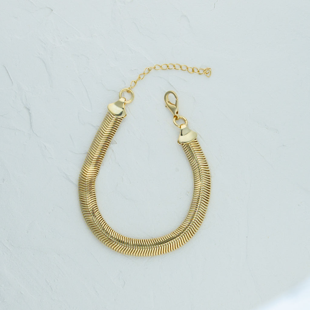 Gold Snake Chain Bracelet - 6mm lying flat on a white surface