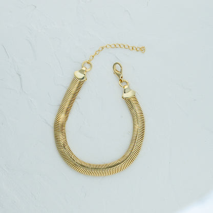 Gold Snake Chain Bracelet - 6mm lying flat on a white surface