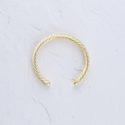 Twisted Gold Bangle lying flat on a white background