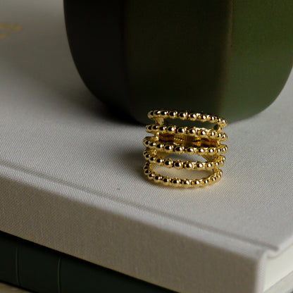 Close-up view showing the intricate beaded strands of the gold ring.